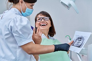 Woman smiling with dentist while reviewing X-ray