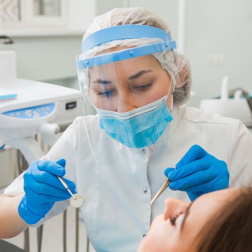 Dental team member wearing protective equipment treating dentistry patient