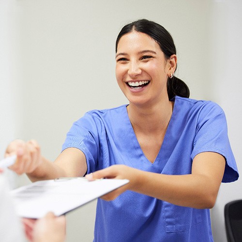 smiling front desk team member holding paperwork