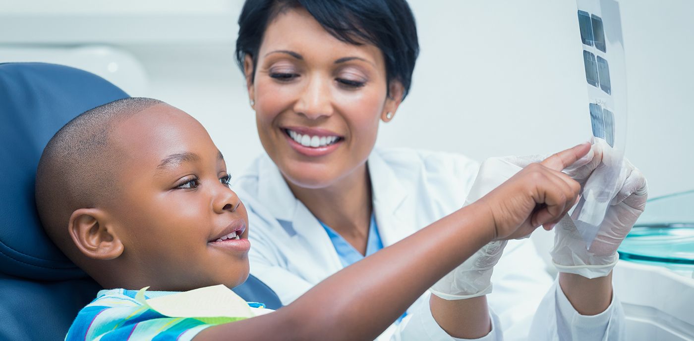 Children's dentist talking to young dental patient