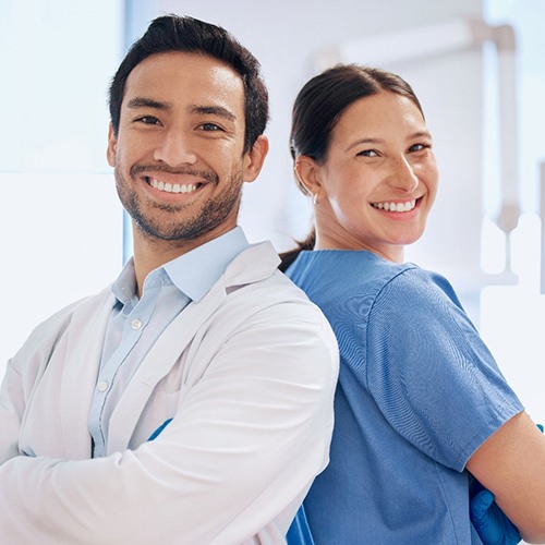 Smiling dentist and team member standing back-to-back