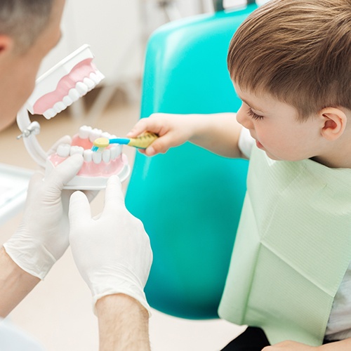 Child practicing tooth brushing during dental checkup and teeth cleaning visit