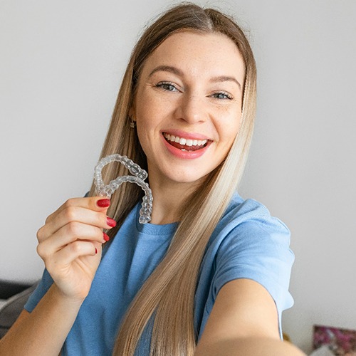 Young woman smiling while holding clear aligners