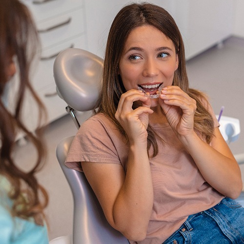 Patient holding clear aligner and smiling at dentist