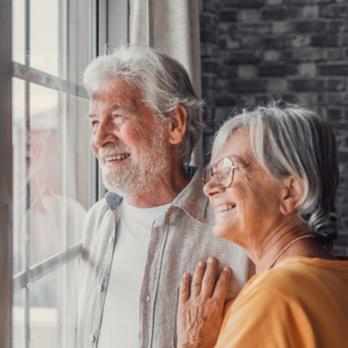 Senior man and woman looking out a window