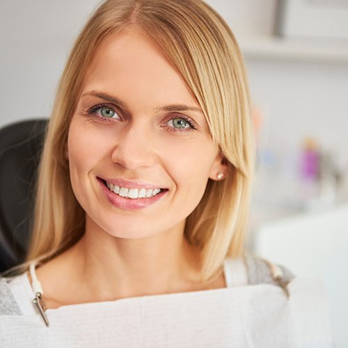 Blonde woman sitting in dental chair smiling