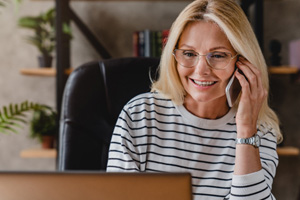 Woman with glasses smiling while talking on phone