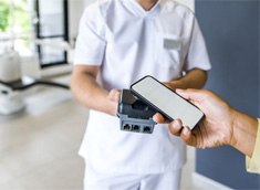 Patient using phone to pay for dental treatment