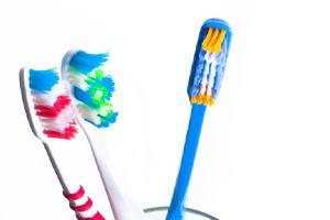 Three colorful toothbrushes in a cup