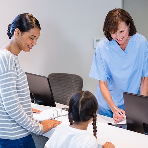 Mother and child checking in at dental office reception desk