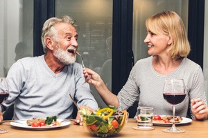 a man with dental implants enjoying a healthy meal