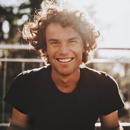 Man in black shirt sitting on bleachers and smiling