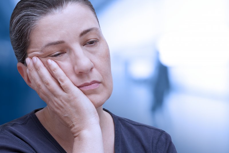 Woman holding her jaw due to needing a root canal